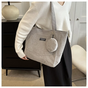 Detail of light gray corduroy tote bag with small coin purse and front pocket label