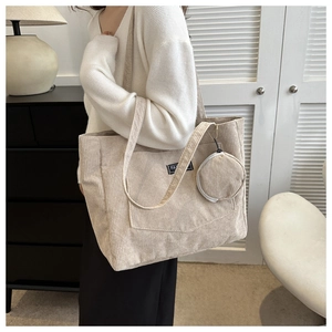 Close-up of beige corduroy tote bag with front pocket and round coin purse detail