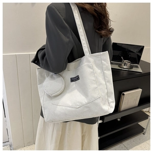 Detail of off-white corduroy tote bag with front pocket and round coin purse accessory