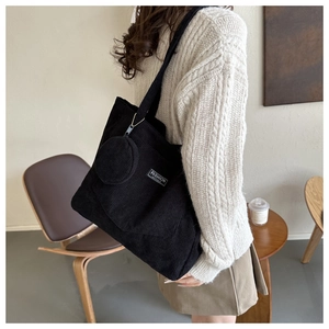 Detail of black corduroy tote bag with decorative label and matching round coin purse