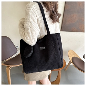 Black corduroy tote bag detail with matching round coin purse and white brand label