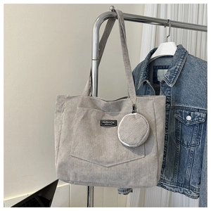 Detail of gray corduroy tote bag with front pocket, round coin purse and fashion label