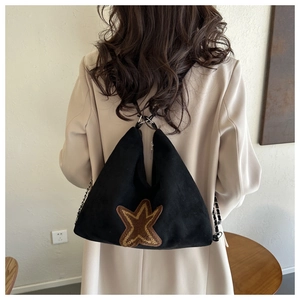 Détail d'un sac cabas noir mat avec écusson étoile et bandoulière en chaîne