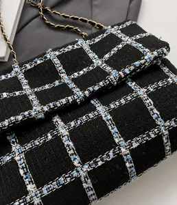 Gedetailleerde close-up van de geweven tweed-textuur en gouden metalen ketting van de tas