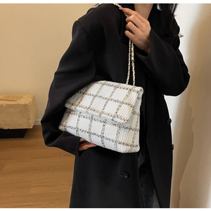 Detail van tweed crossbody tas met gouden kettingriem op een zwarte blazer outfit