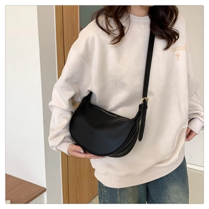 Detail view of the black crescent bag with golden buckle and smooth leather finish