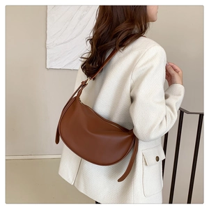 Detail of dark brown crescent bag with adjustable strap worn with white tweed jacket