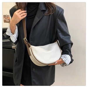 Detailed side view of white crescent bag with brown trim and adjustable strap on a model