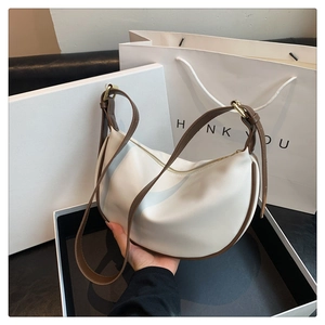 Detail of cream crescent hobo bag with brown leather strap and golden hardware