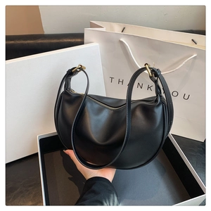 Detail of black PU leather hobo bag with gold hardware and metal zipper closure
