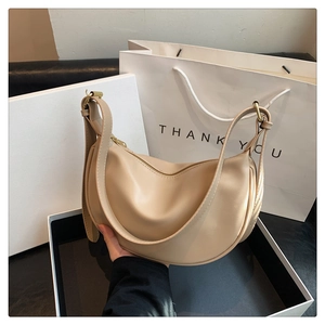 Detail of beige hobo bag showing smooth leather texture and gold adjustable buckle