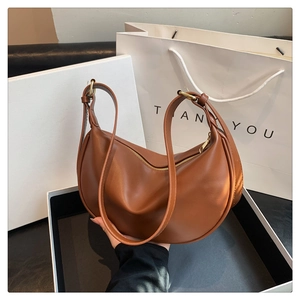 Detailed view of a brown faux leather crescent bag with smooth texture and golden zipper