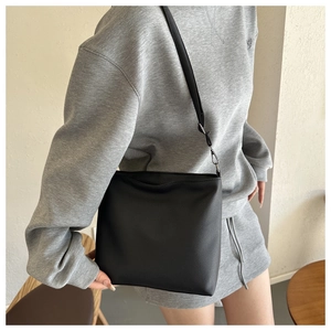 Close-up of black litchi grain leather shoulder bag with neat stitching and adjustable strap
