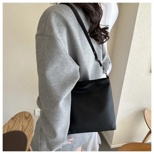 Close-up of black lychee grain leather bucket bag showing soft texture and strap detail
