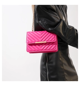Close-up of a stylish hot pink chevron quilted underarm bag with gold chain strap