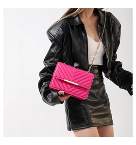 Detail of vibrant pink chevron quilted chain bag worn over a black leather jacket