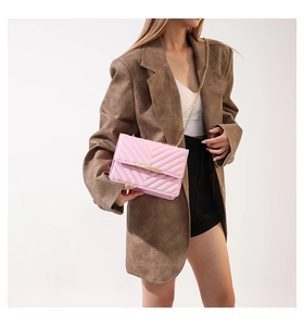 Detail of pink quilted handbag with V-stitch pattern and gold chain on model shoulder