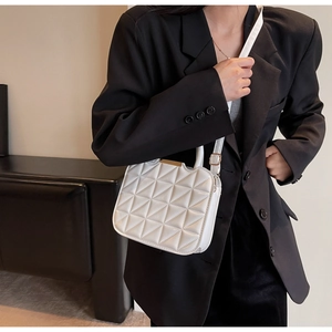Detail of white quilted crossbody bag featuring 3D geometric triangular stitching pattern