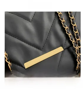 Detailed macro view of black quilted faux leather with V-shaped stitching and gold metal buckle