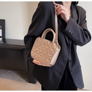 Detail of beige quilted leather handbag with triangle stitching shown on a model