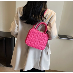 Detail of fuchsia quilted handbag with rhombic stitching and metal trim on the opening