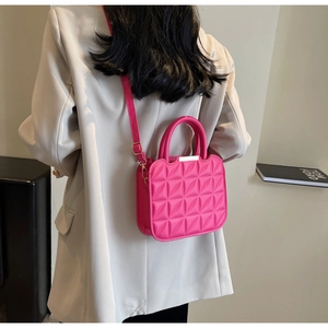Detail of pink quilted rhombic pattern handbag with gold hardware and shoulder strap
