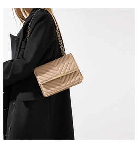 Chic beige chevron quilted crossbody bag with gold chain strap on model in black blazer