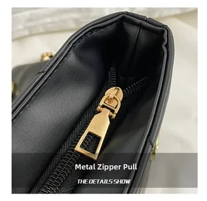 Detail shot of a premium golden metal zipper puller on a black leather shoulder bag