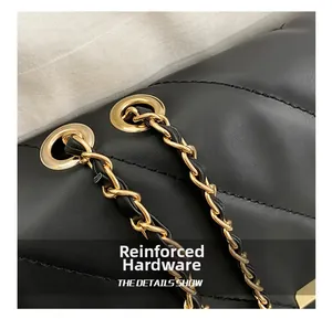 Macro view of reinforced gold-tone chain hardware on black quilted leather bag