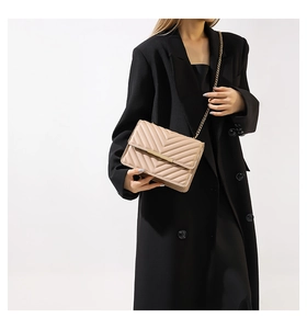 Close-up of beige V-quilted leather chain shoulder bag with a gold metal clasp buckle