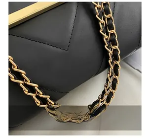 Detail of black V-quilted leather bag with gold hardware and woven chain strap