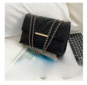 Detail of black quilted crossbody bag with gold rectangular clasp and chain strap