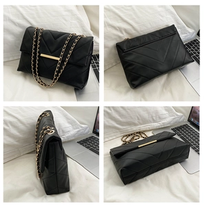 Detail view of black crossbody bag with V-shaped quilting and gold chain strap