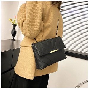 Chic black V-quilted shoulder bag with gold chain strap styled on a camel blazer