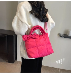 Hot pink quilted tote bag with bow detail worn by a model in casual home setting