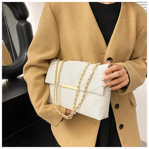 Close-up of white quilted handbag with golden chain strap and rectangular metal lock