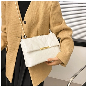 Detail showing white quilted crossbody bag with gold chain strap and metal lock closure
