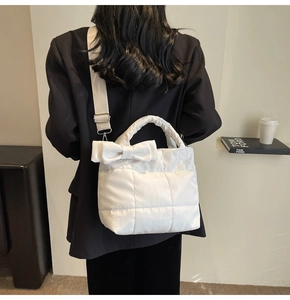 Detail of white quilted tote bag featuring a large bow and soft puffer texture nylon fabric