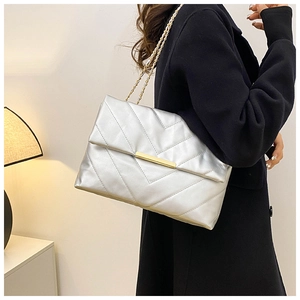 Detail of silver quilted shoulder bag featuring V-shaped stitching and gold chain strap