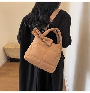 Detailed shot of brown quilted tote bag with bow accent worn over the shoulder