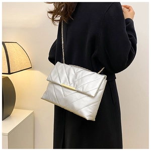 Detail of silver quilted shoulder bag with gold chain strap and metal clasp on model