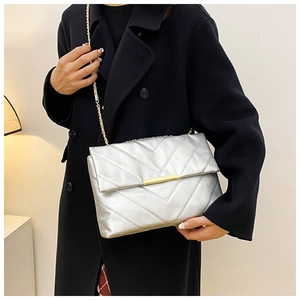 Silver quilted shoulder bag with chain strap and V-pattern stitching on black coat