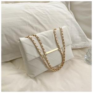 Close-up of white quilted leather bag with golden chain strap and minimal metal buckle