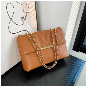 Detail of caramel quilted shoulder bag with V-shaped stitching and gold chain straps