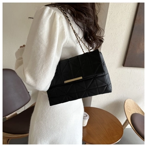 Détail du sac à bandoulière matelassé noir avec chaîne dorée et boucle métallique chic