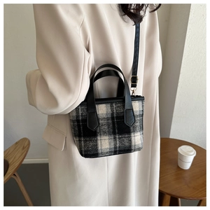 Detail of vintage plaid bucket bag with black leather handle and adjustable strap