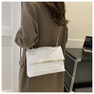 Détails de la texture en cuir blanc matelassé et chaîne dorée sur un sac bandoulière chic
