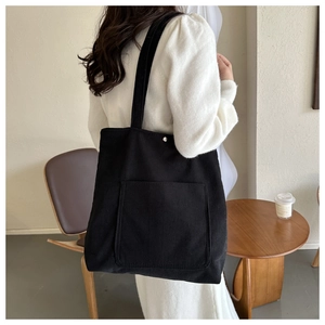 Detail of black corduroy tote bag with magnetic closure and large front pocket