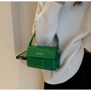 Detail showing bright green square embossed handbag with white fashion text on the flap