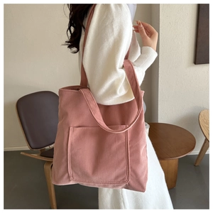 Close-up of pink corduroy tote bag showing soft ribbed texture and large front pocket
